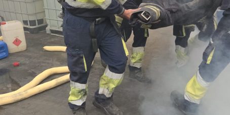 Equipo de participantes con equipos de respiración autónoma transportando un maniquí durante una simulación